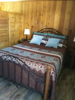 a bedroom with a large bed with wooden walls at Kern Riverfront Lodge in Kernville