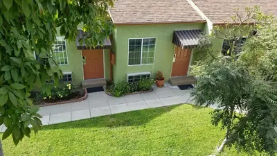 a green house with a red door and a yard at Victory Motel Inn near Universal & Hollywood in Glendale