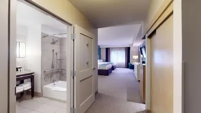 a room with a bathroom with a tub and a bed at SunCoast Hotel Anaheim, Tapestry Collection by Hilton in Anaheim