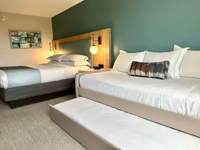 a hotel room with two beds and a couch at SunCoast Hotel Anaheim, Tapestry Collection by Hilton in Anaheim