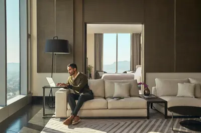 a man sitting on a couch with a laptop at InterContinental - Los Angeles Downtown by IHG in Los Angeles