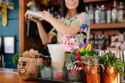 a woman behind a counter in a bar with flowers in cups at Freehand Los Angeles in Los Angeles