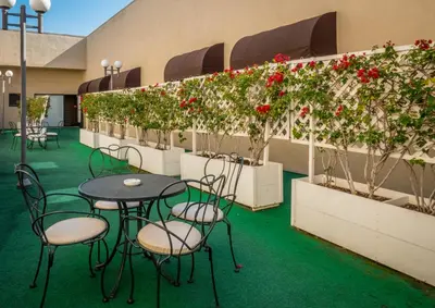 a patio with tables and chairs and red flowers at Olyver Hotel in Los Angeles