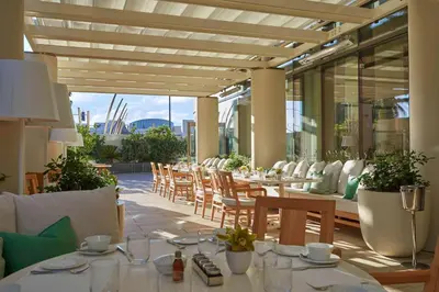 a restaurant with tables and chairs on a patio at Waldorf Astoria Beverly Hills in Los Angeles