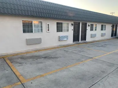 a white building with black doors in a parking lot at Empire Inn in Los Angeles