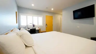 a white bed with white pillows in a bedroom at El Royale Gardens Near Universal Studios in Los Angeles
