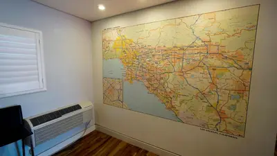 a large map on a wall next to a fan at El Royale Gardens Near Universal Studios in Los Angeles