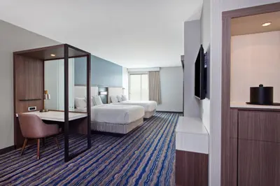 a hotel room with two beds and a desk and a television at SpringHill Suites by Marriott Huntington Beach Orange County in Huntington Beach