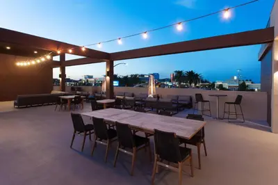 a patio with a table and chairs on a roof at SpringHill Suites by Marriott Huntington Beach Orange County in Huntington Beach