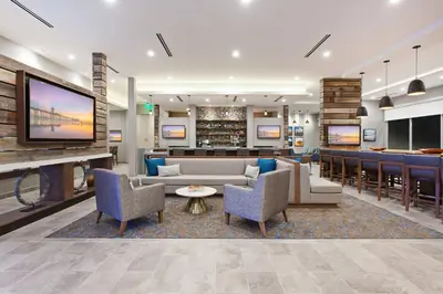 a hotel lobby with a couch and chairs and a bar at SpringHill Suites by Marriott Huntington Beach Orange County in Huntington Beach