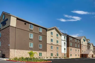 a large brick building with a parking lot at WoodSpring Suites Bakersfield East in Bakersfield