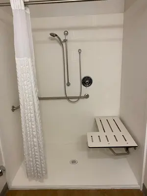 a bathroom with a shower and a bench in it at WoodSpring Suites Bakersfield East in Bakersfield