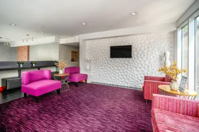 a waiting room with pink chairs and a tv at Lexen Hotel - Hollywood Walk of Fame-Universal Studios in Los Angeles