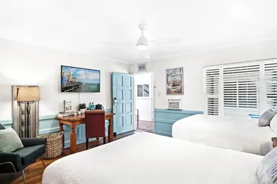 a hotel room with two beds and a desk at Sea Blue Hotel in Los Angeles