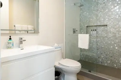 a bathroom with a toilet and a glass shower at Park Plaza Lodge in Los Angeles