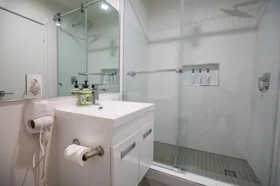 a white bathroom with a shower and a sink at Park Plaza Lodge in Los Angeles