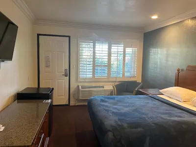 a bedroom with a bed and a desk and a window at Welcome Inn in Los Angeles
