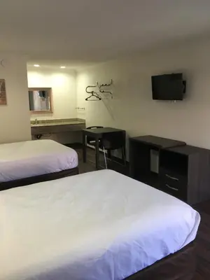 a hotel room with two beds and a desk and a television at Baymont by Wyndham Bakersfield in Bakersfield