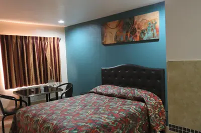 a bedroom with a bed and a table in a room at Florentina Motel - Los Angeles in Los Angeles