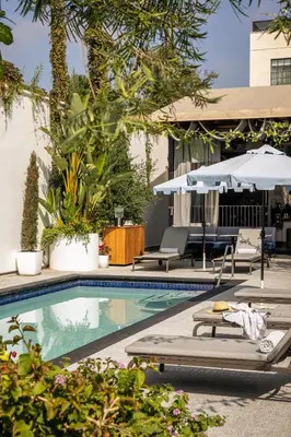 a swimming pool with lounge chairs and umbrellas at Kimpton La Peer Hotel West Hollywood by IHG in Los Angeles