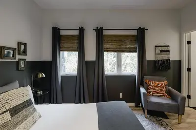 a bedroom with a bed and a chair and windows at Noon on Sunset Hill in Los Angeles