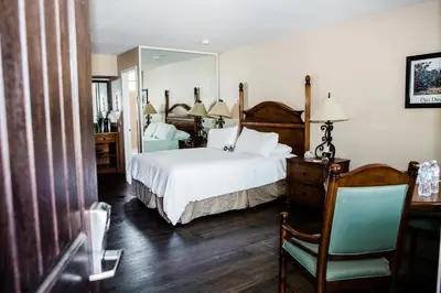 a bedroom with a bed and a mirror and a chair at Casa Ojai Inn in Ojai