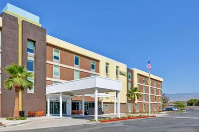a hotel with palm trees in front of a building at Home2 Suites Azusa in Azusa