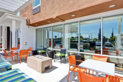 a patio with tables and chairs and windows at Home2 Suites Azusa in Azusa