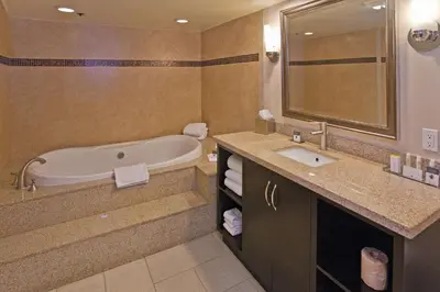 a bathroom with a tub and a sink and a mirror at DoubleTree by Hilton Rosemead in Rosemead