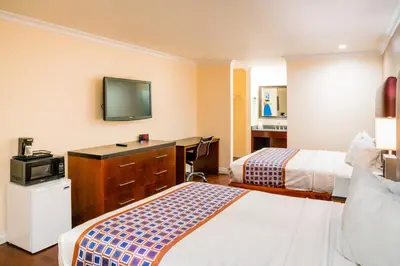 a hotel room with two beds and a desk at Gateway Inn Gardena Los Angeles South in Gardena