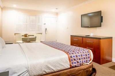 a bedroom with a bed and a flat screen tv at Gateway Inn Gardena Los Angeles South in Gardena