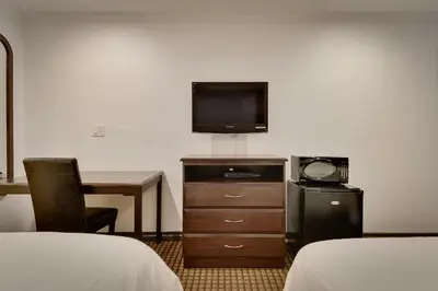 a hotel room with a tv and a desk and a bed at Vagabond Inn San Pedro in San Pedro