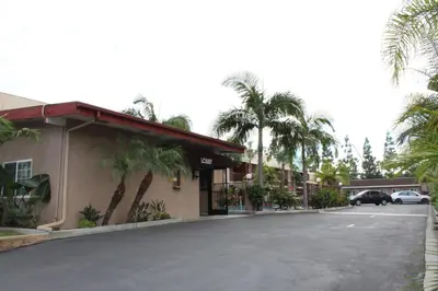 a parking lot in front of a hotel with palm trees at Budget Inn Anaheim near Disneyland Drive in Anaheim