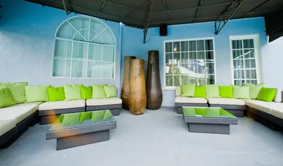 a living room with green seats and windows at Hotel Current in Long Beach