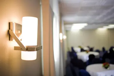 a light on a wall in a room with tables at Hotel Current in Long Beach