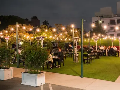 a group of people sitting at tables in a park at night at Hollywood Historic Hotel in Los Angeles