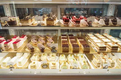 a display case filled with different types of cakes and pastries at Hollywood Historic Hotel in Los Angeles
