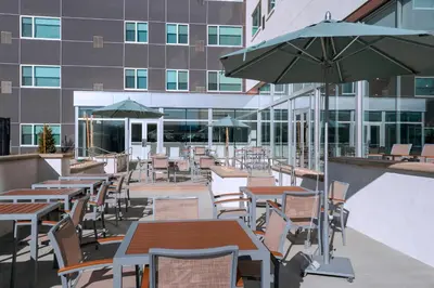 an outdoor patio with tables and chairs and an umbrella at Element Palmdale in Palmdale