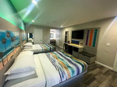 a bedroom with two beds and a desk and a television at Wave Hotel Manhattan Beach in Manhattan Beach