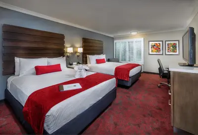 a hotel room with two beds and a flat screen tv at Desert Palms Hotel & Suites Anaheim Resort in Anaheim