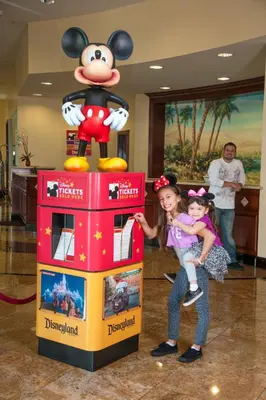 a woman and a girl standing next to a mickey mouse machine at Desert Palms Hotel & Suites Anaheim Resort in Anaheim