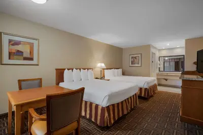 a hotel room with two beds and a desk at Best Western Norwalk Inn in Norwalk