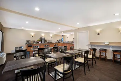 a restaurant with tables and chairs and a kitchen at Best Western Norwalk Inn in Norwalk