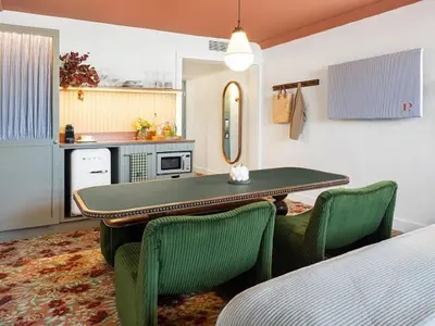 a dining room with a table and two green chairs at Palihouse West Hollywood at Beverly Hills in Los Angeles