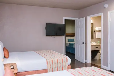 a hotel room with two beds and a flat screen tv at Alamo Inn and Suites - Convention Center in Anaheim