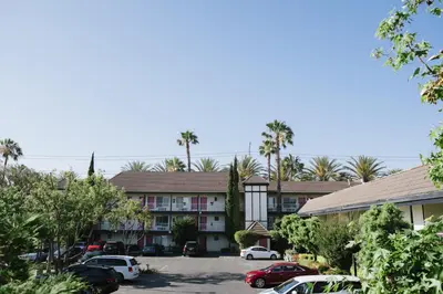 a parking lot in front of a building with palm trees at Alamo Inn and Suites - Convention Center in Anaheim