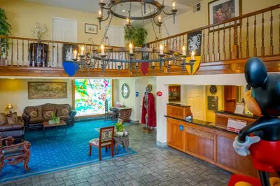 a large living room filled with furniture and a staircase at Castle Inn and Suites Anaheim in Anaheim