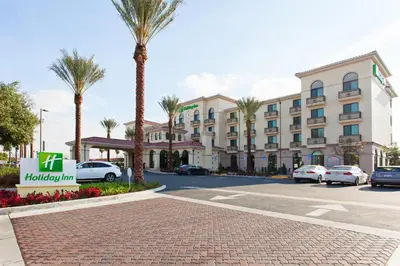 a hotel with palm trees in front of a parking lot at Holiday Inn El Monte - Los Angeles by IHG in El Monte