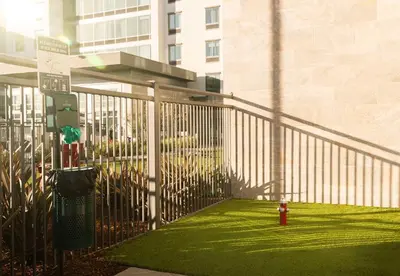 a fence with a red fire hydrant in front of a building at Hampton Inn Long Beach Airport, Ca in Long Beach