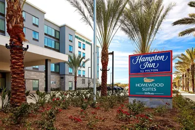 a sign in front of a hotel with palm trees at Homewood Suites By Hilton Long Beach Airport in Long Beach